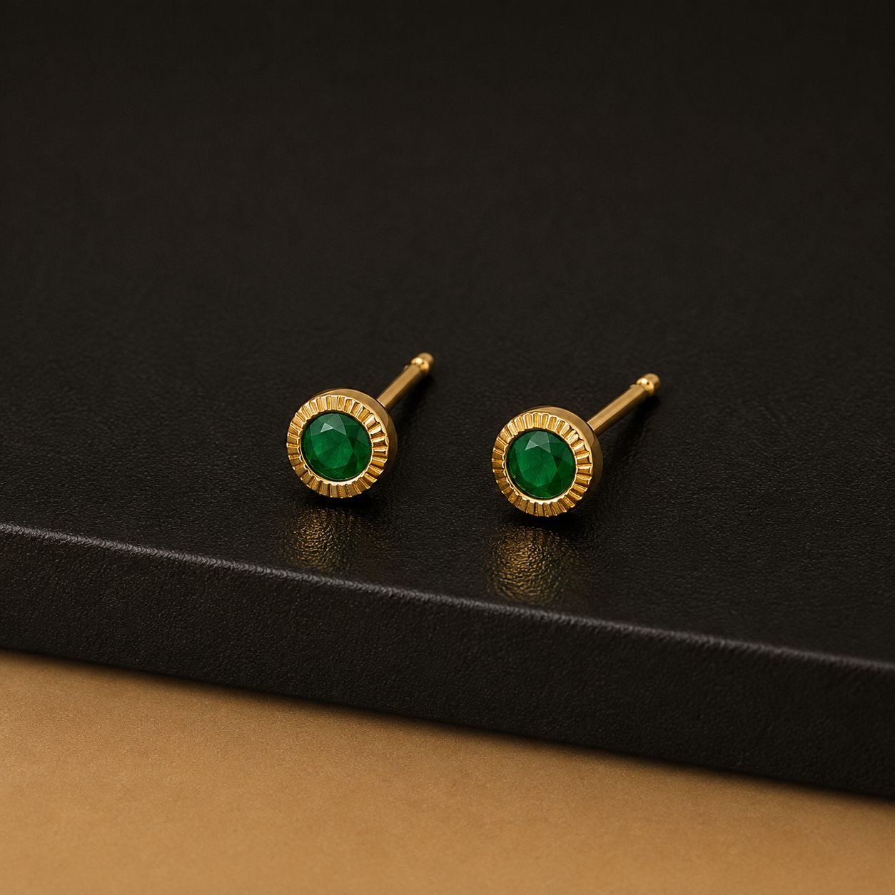 Gold stud earrings with green stones in a fluted gold halo