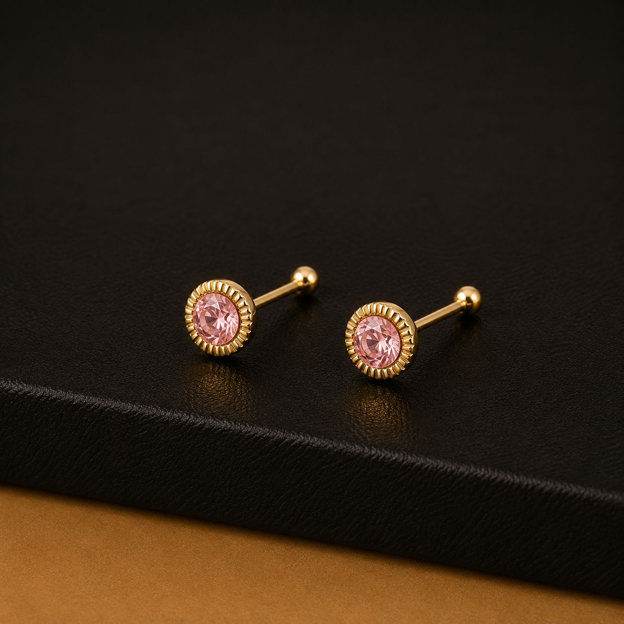 Gold stud earrings with pink stones in a fluted gold halo