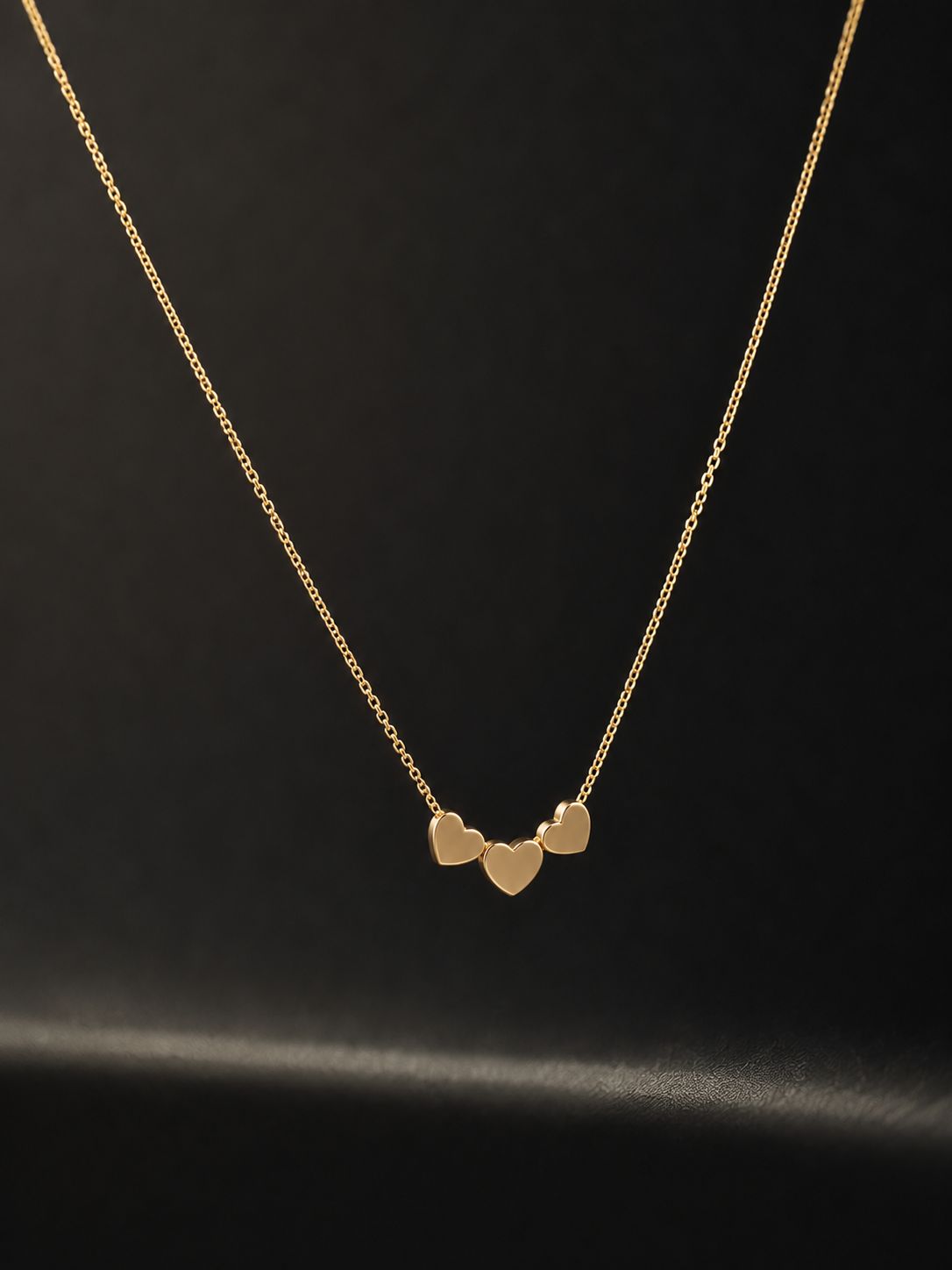 Gold necklace with three polished hearts linked side by side