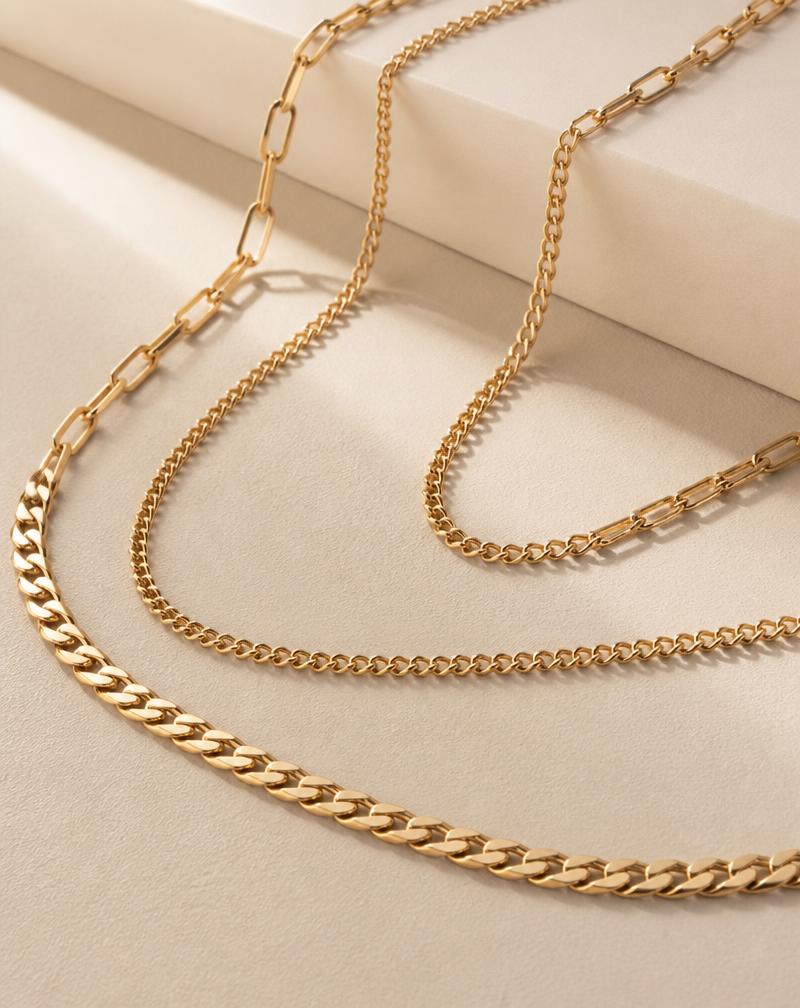 Solid 10K gold chain necklaces laid on a cream background