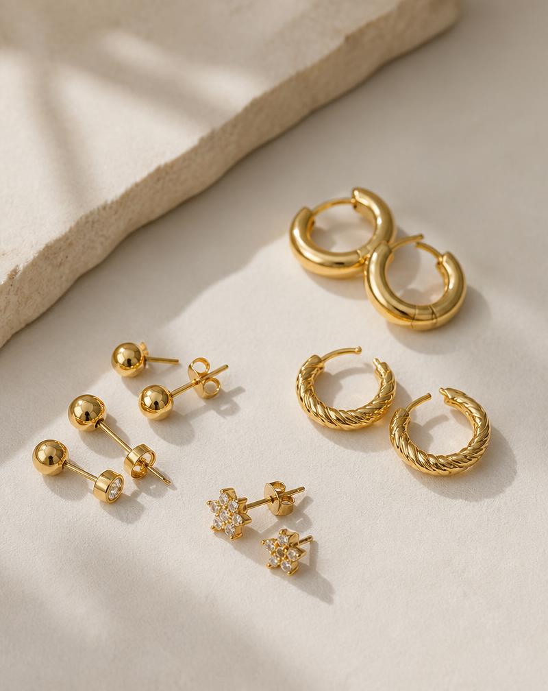Solid 10K gold hoop and stud earrings on a cream background