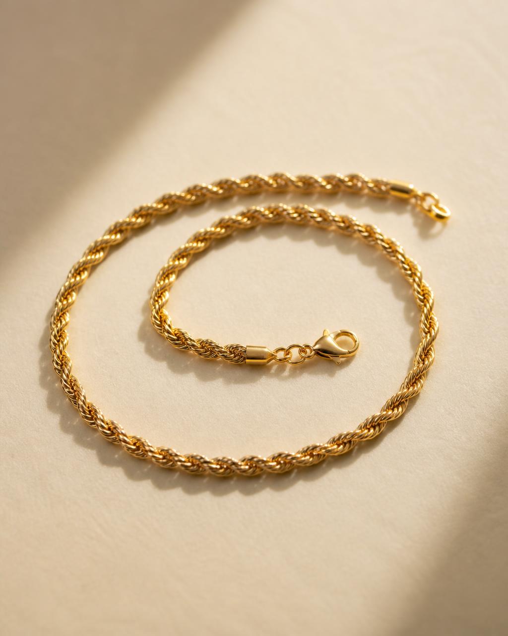 Solid gold rope chain coiled on a dark stone surface